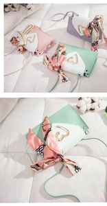 Detail of crossbody bags in pink, purple and green with heart buckles and silk scarves