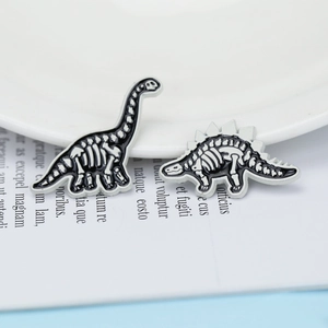 Macro detail of dinosaur skeleton pins in black and white enamel on a magazine