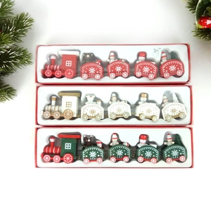 Flat lay of three wooden Christmas trains in red, white, and green with festive pine decor