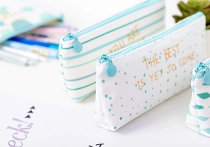 Close-up of canvas pencil cases with gold foil prints, mint green patterns, and zippers