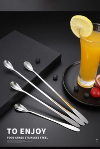 Long handle stainless steel mixing spoons on dark geometric blocks with fresh citrus