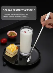 Close-up of long-handled stainless steel spoon being used in a tall glass with dessert