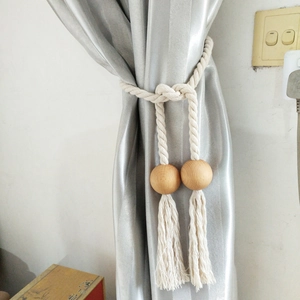 Detail of wooden beads and beige woven rope tieback on silver grey curtain