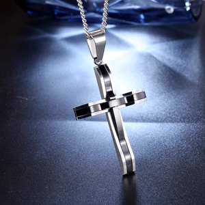 Polished black and silver stainless steel cross pendant with silver chain on dark background