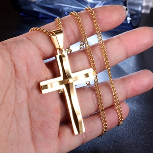 Close-up of a minimalist golden stainless steel cross necklace held in hand