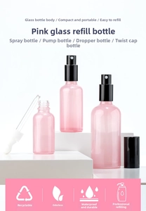 Pink glass spray and dropper bottles displayed on geometric stands for cosmetics