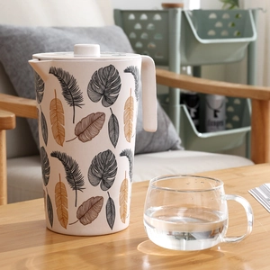 Bamboo fiber cold water pitcher with tropical leaf print and white lid on wooden table