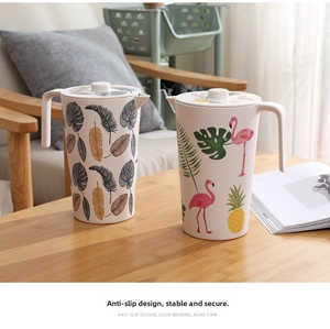 Bamboo fiber pitchers with tropical leaves and flamingo prints on a wooden table