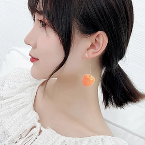 Close-up of a model wearing sweet orange cherry-shaped long drop earrings for women