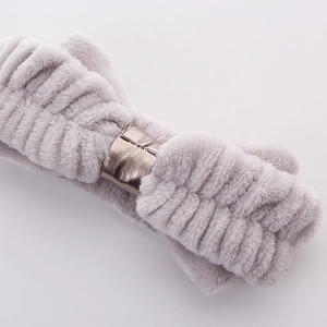 Detail of grey plush headband with a gold bow decoration for skincare and makeup