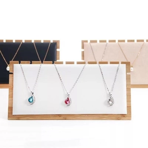 Bamboo necklace display stand with white panel featuring three silver pendant necklaces