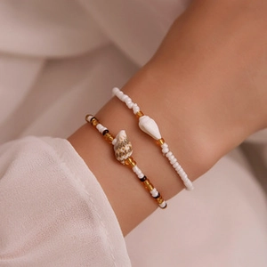 Close-up of beaded bracelets with natural shell charms worn on a woman's wrist