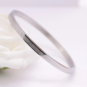 Macro shot of silver stainless steel cuff bracelet with Greek Meander pattern and floral accent