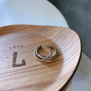 Macro view of minimalist 925 silver beaded chain ring on a textured wooden stand