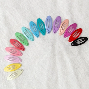 Macro view of 14 colorful 2.5cm teardrop metal BB hair clips in a semi-circular layout