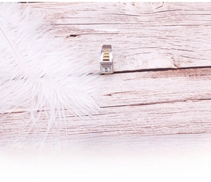 Close-up of silver and gold titanium ring with round zircon and grooved textures