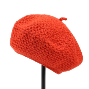 Detailed macro view of bright orange hand-crocheted wool beret with thick knit texture