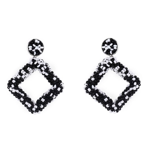 Detail of handmade geometric diamond-shaped beaded earrings with black and white checkerboard pattern