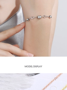 Detail of waist-shaped metal bracelets in silver, gold and rose gold on white feathers