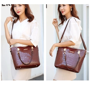 Detailed view of dark brown faux crocodile leather handbag with double handles and gold metal accents