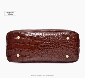 Detailed bottom view of brown crocodile texture bag with four golden protective metal feet