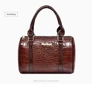 Detail of dark brown crocodile texture Boston handbag with glossy finish and metal logo
