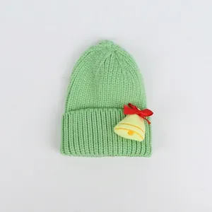 Dettaglio del cappello di Natale in maglia verde con campana gialla e fiocco rosso