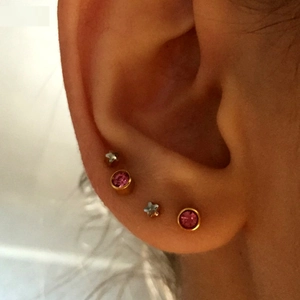 Detailed view of pink zircon flower stud earrings set in gold finish on ear