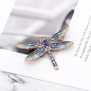 Macro detail of golden dragonfly brooch with blue enamel and sparkling rhinestones