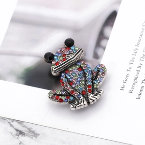 Macro shot of silver frog brooch with colorful rhinestones on marble background