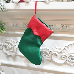 Green and red satin Christmas stocking hanging on a white fireplace for holiday decor