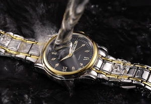 Close-up of dual-tone steel watch with Roman numerals being splashed by water