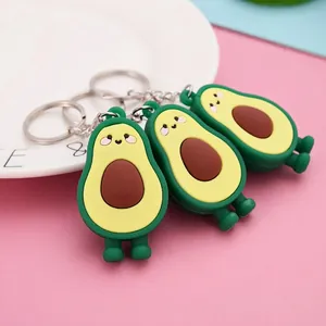 Three cute avocado PVC keychains with smiling faces on a white plate with pink background