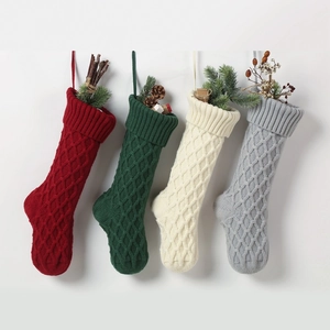 Detail von vier gestrickten Weihnachtsstrümpfen mit Rautenmuster in festlichen Farben