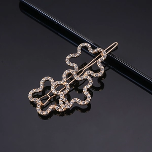 Macro view of gold plated hair clip with sparkling rhinestones and hollow floral pattern