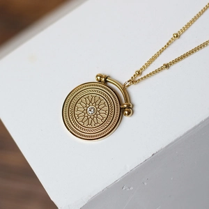 Macro shot of 18K gold plated coin pendant with central crystal and satellite chain detail