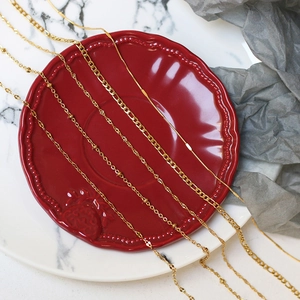 Close-up of assorted gold titanium steel necklaces on a red ceramic plate