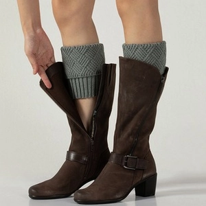 Detail of grey cable knit leg warmers showing textured 8-character twist pattern on boots