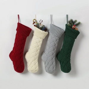 Row of four knitted Christmas stockings in red, cream, grey and dark green colors