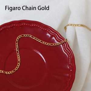 Detailed view of golden Figaro chain necklace with classic alternating links on ceramic