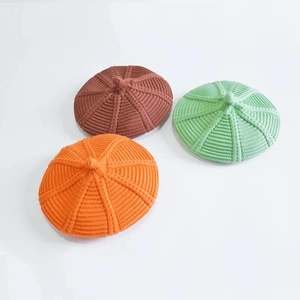 Kids knitted beret hats in orange, brown, and mint green colors for autumn and winter