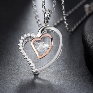 Macro shot of two-tone heart pendant necklace with dancing stone and pavé zircon settings