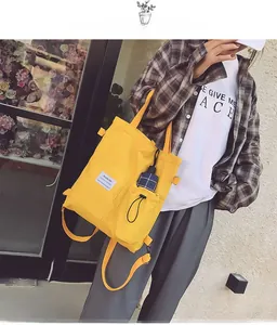 Detail of yellow canvas tote bag with side pocket and Fashion label for school