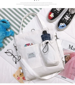 Detail of white canvas tote bag with adjustable shoulder strap and side drawstring pocket