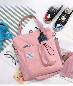 Pink canvas crossbody bag detail showing double front pockets for phone and umbrella