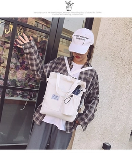 Detailed view of white canvas crossbody bag with multiple pockets and fashion label detail