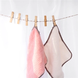 Pink and white microfiber coral fleece towels with check borders hanging on clips