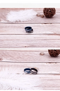 Detail view of two-tone stainless steel rings in blue and black with inlaid crystals