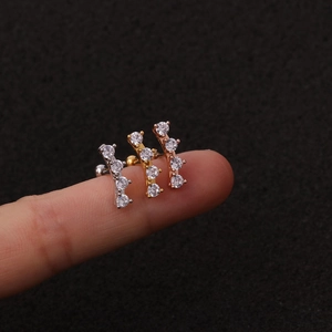 Dettaglio macro di tre orecchini a fiore in zircone in argento, oro e oro rosa su un dito