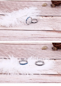 Detail of silver, blue, and black titanium steel rings with rhinestones on wood